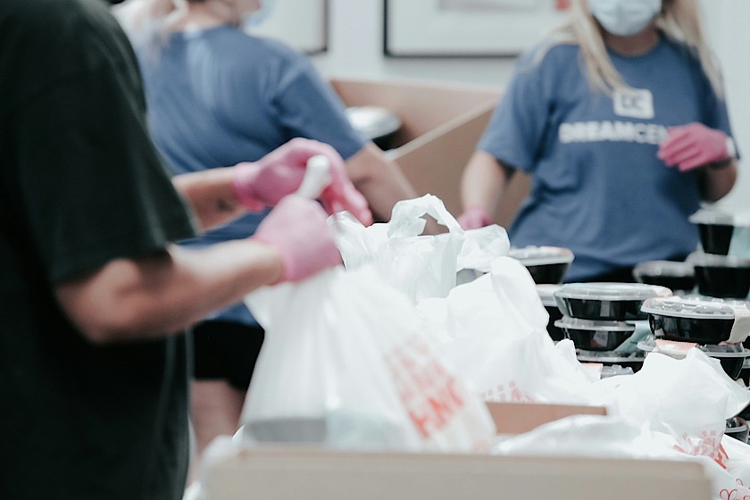 Mehrere ehrenamtliche Helferinnen und Helfer verpacken gemeinsam Lebensmittel.