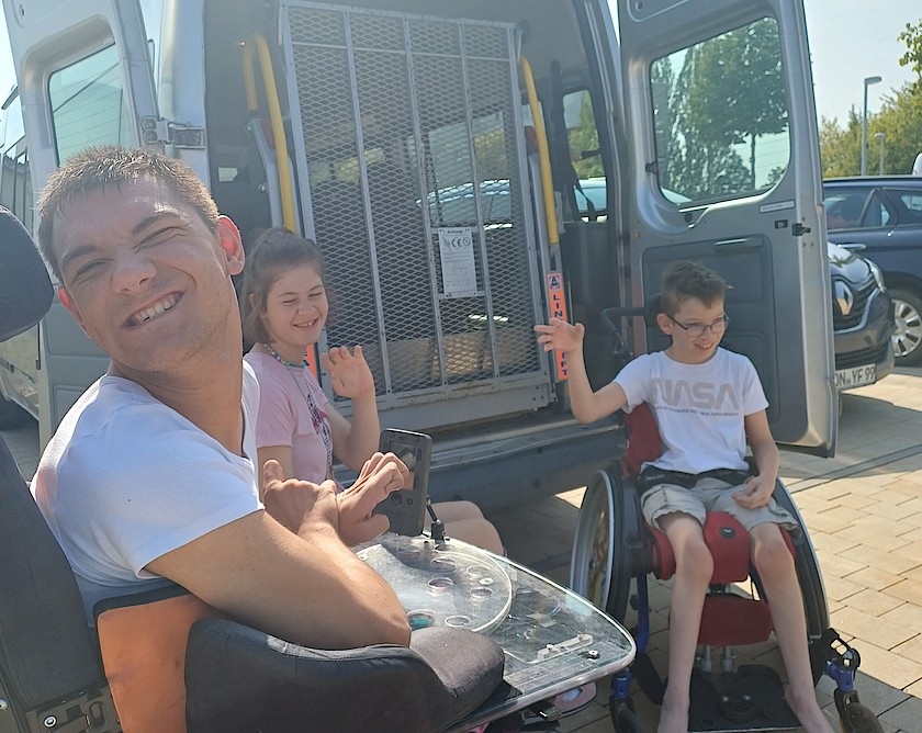 3 fröhliche Kinder vor einem weißen Kleinbus